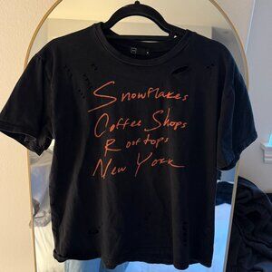 M//C Black Tee with Orange Writing "Snowflakes, Coffee Shops, Rooftops, NY"